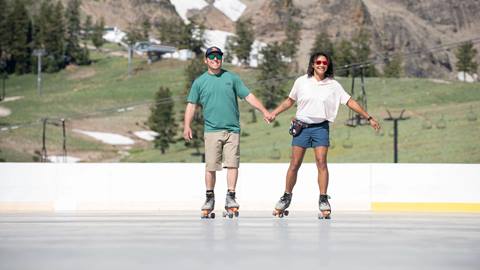 Couple holding hands and roller skating at Palisades Tahoe