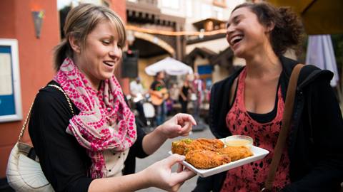 Two women enjoying a plate of fried chicken wings