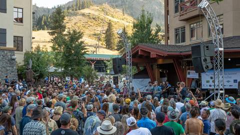 A band playing for a large crowd at Foam Fest at Squaw Valley with mountain in the background