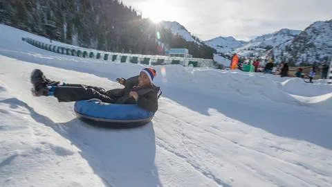 Young kid in an inflatable tube sliding down a snowy chute at Squaw Valley