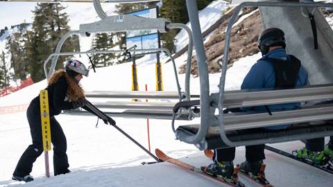 Lift operator clears snow in front of lift at Palisades Tahoe.