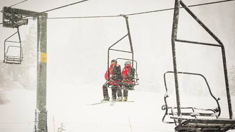 Two ski patrollers ride a lift at Alpine getting ready to perform snow safety