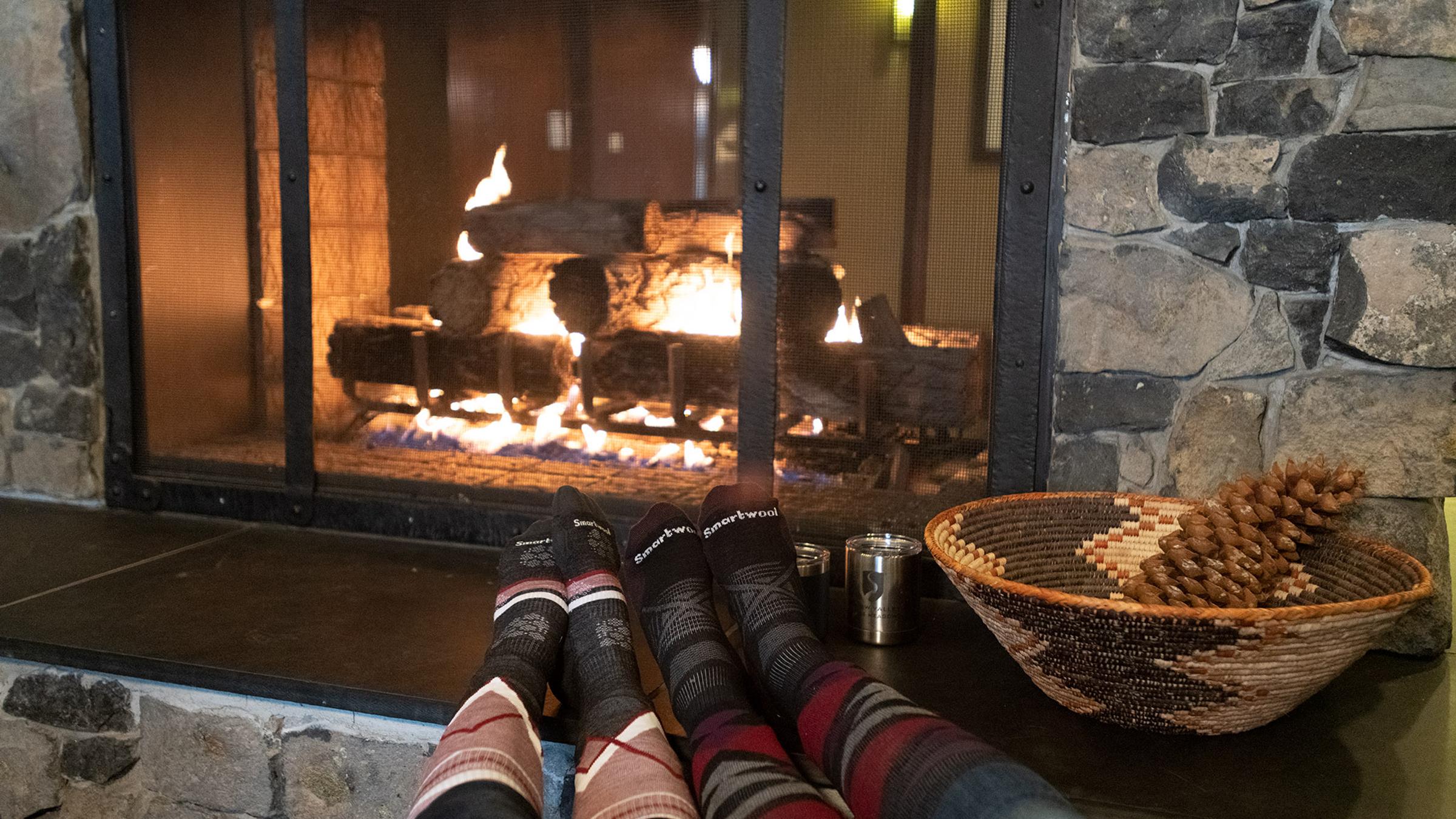 two people warming their feet by the fire in the lobby at the village at squaw valley