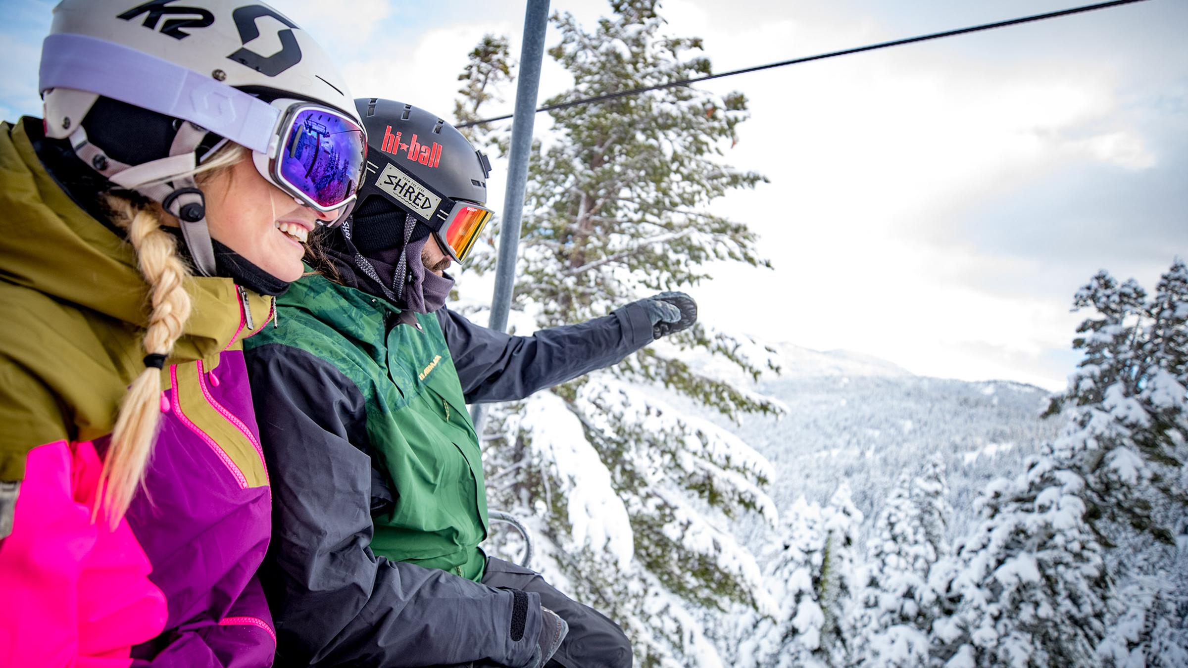 Two skiers on the chairlift checking out the terrain