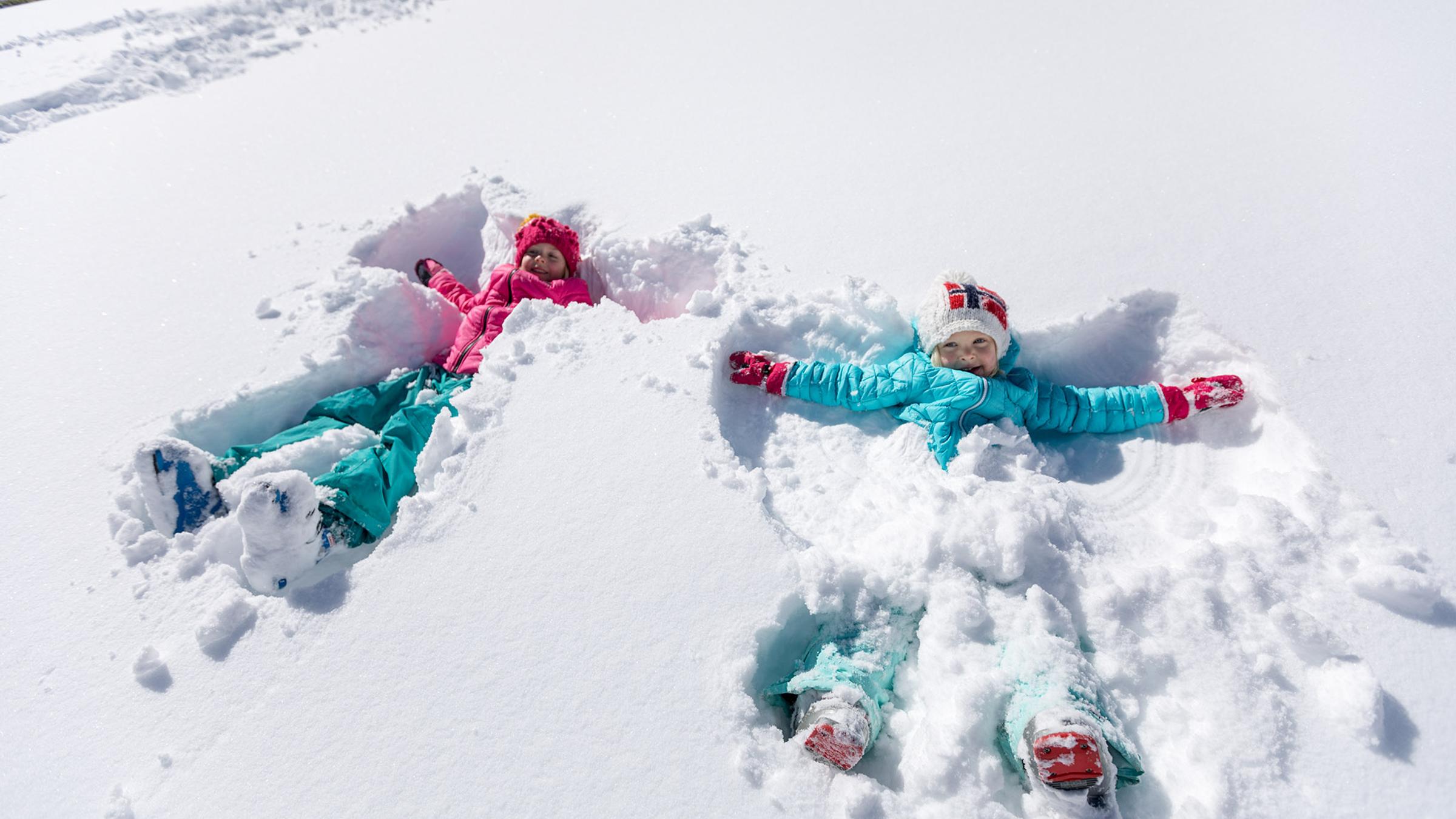 Two girls doing snow angels at alpine meadows