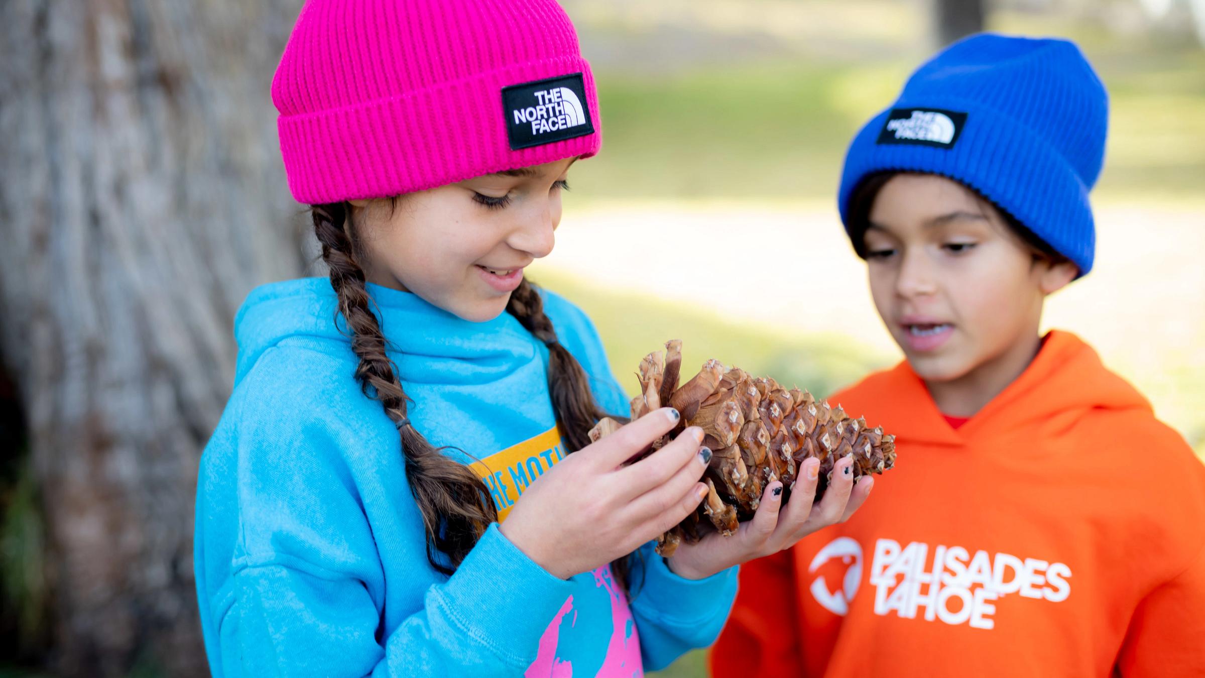 Two kids wear new Palisades Tahoe sweatshirts and hats from The North Face.