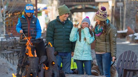 Family roasting smores & drinking hot chocolate at the firepit in the village at squaw valley.