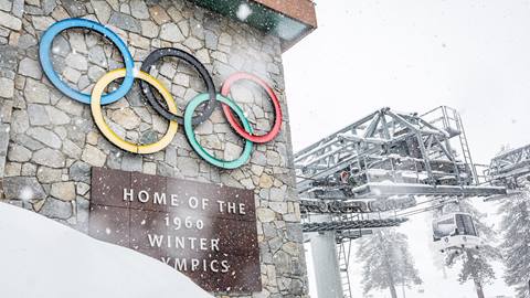 Snow flying in front of the olympic rings on the funitel base terminal