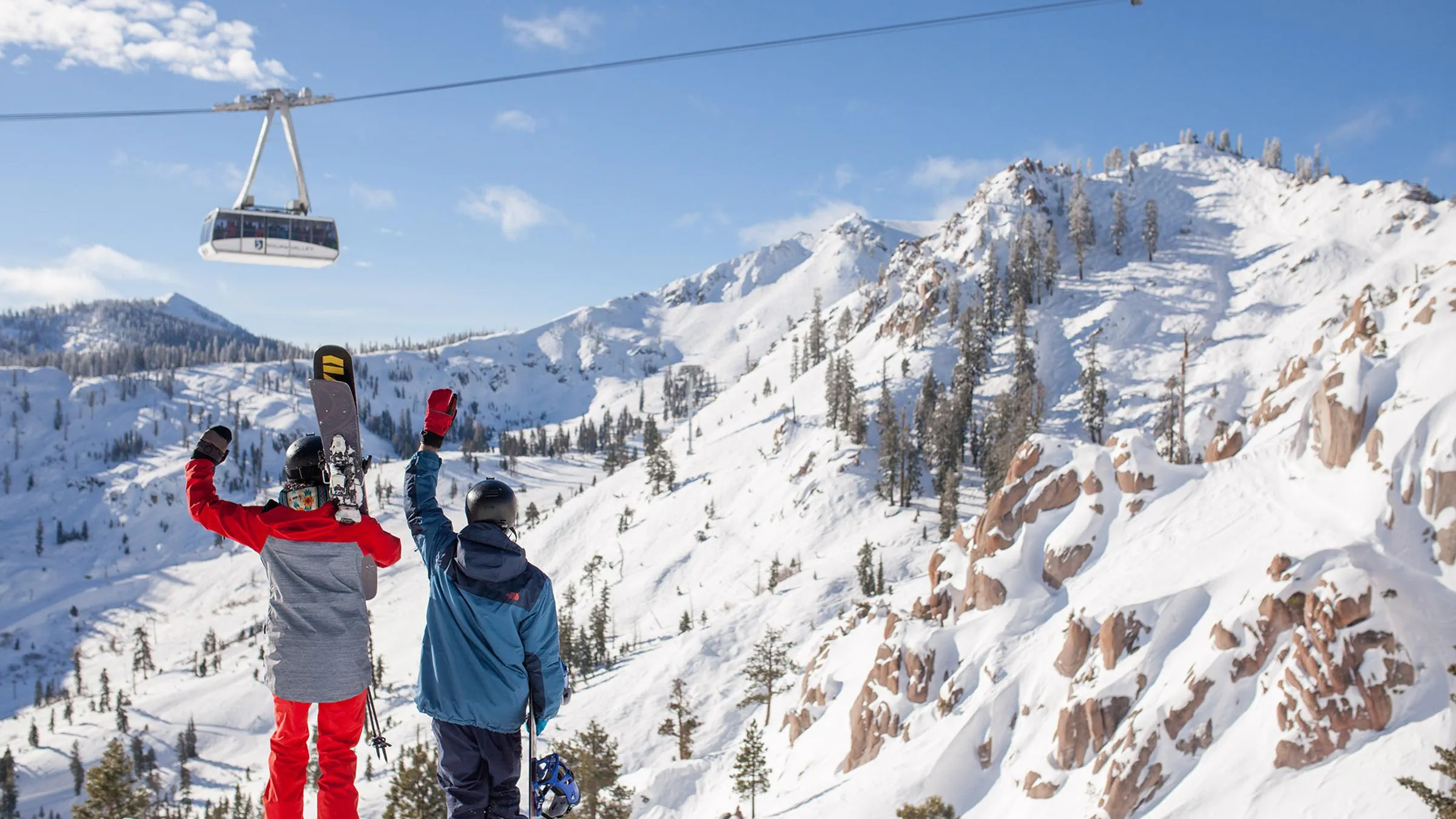Aspirational lifestyles of a skier and a snowboarder waving to aerial Tram at Squaw Valley