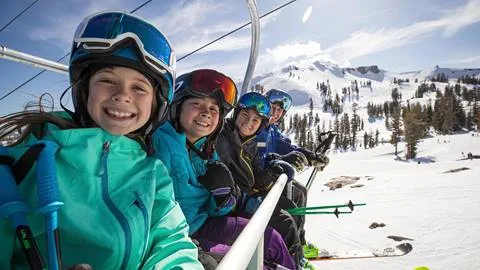 Kids smiling on a chairlift during a ski lesson at Squaw Valley Alpine Meadows