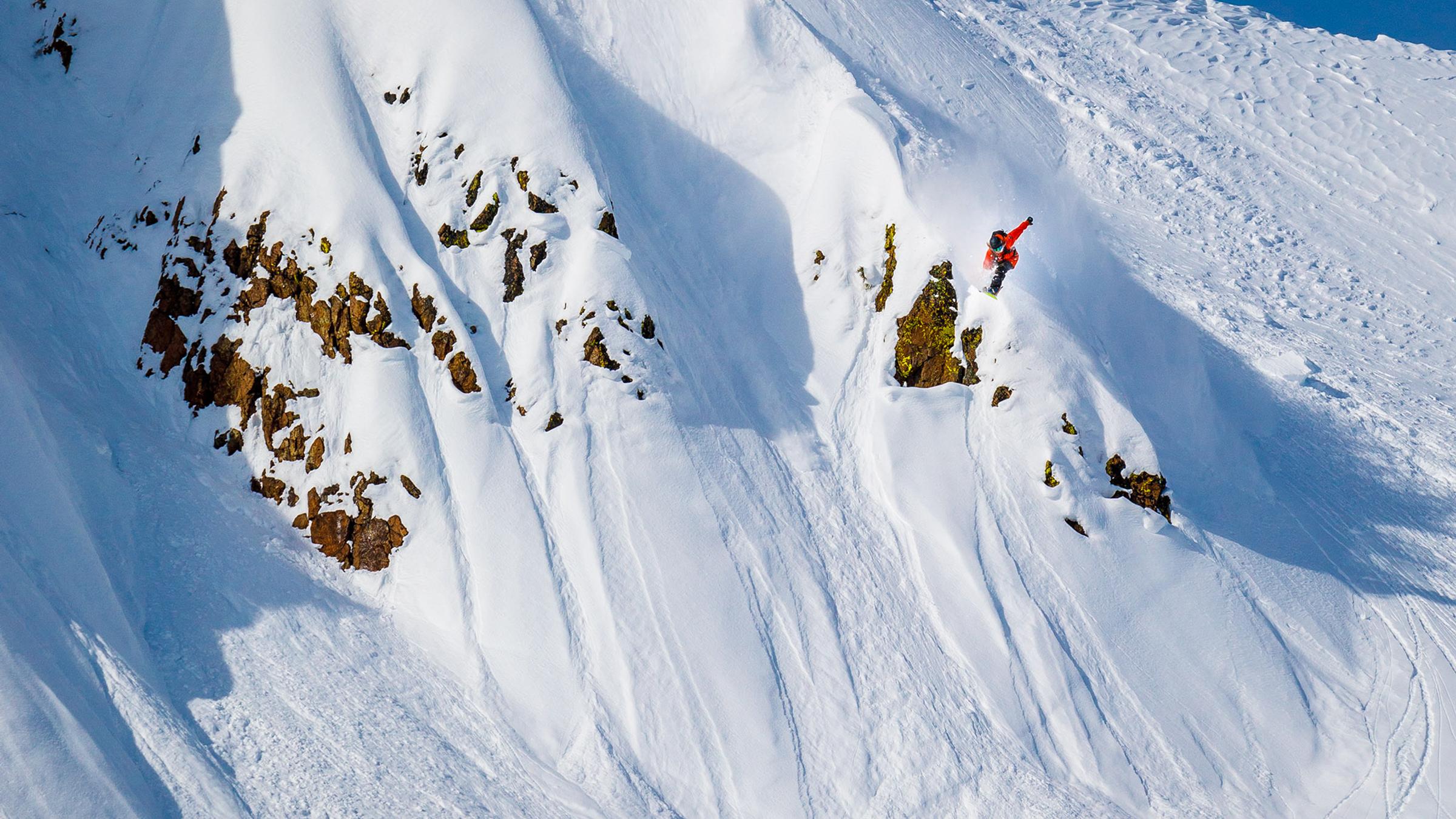 Tim Humphreys snowboarding & airing a cliff into powder at Apine Meadows