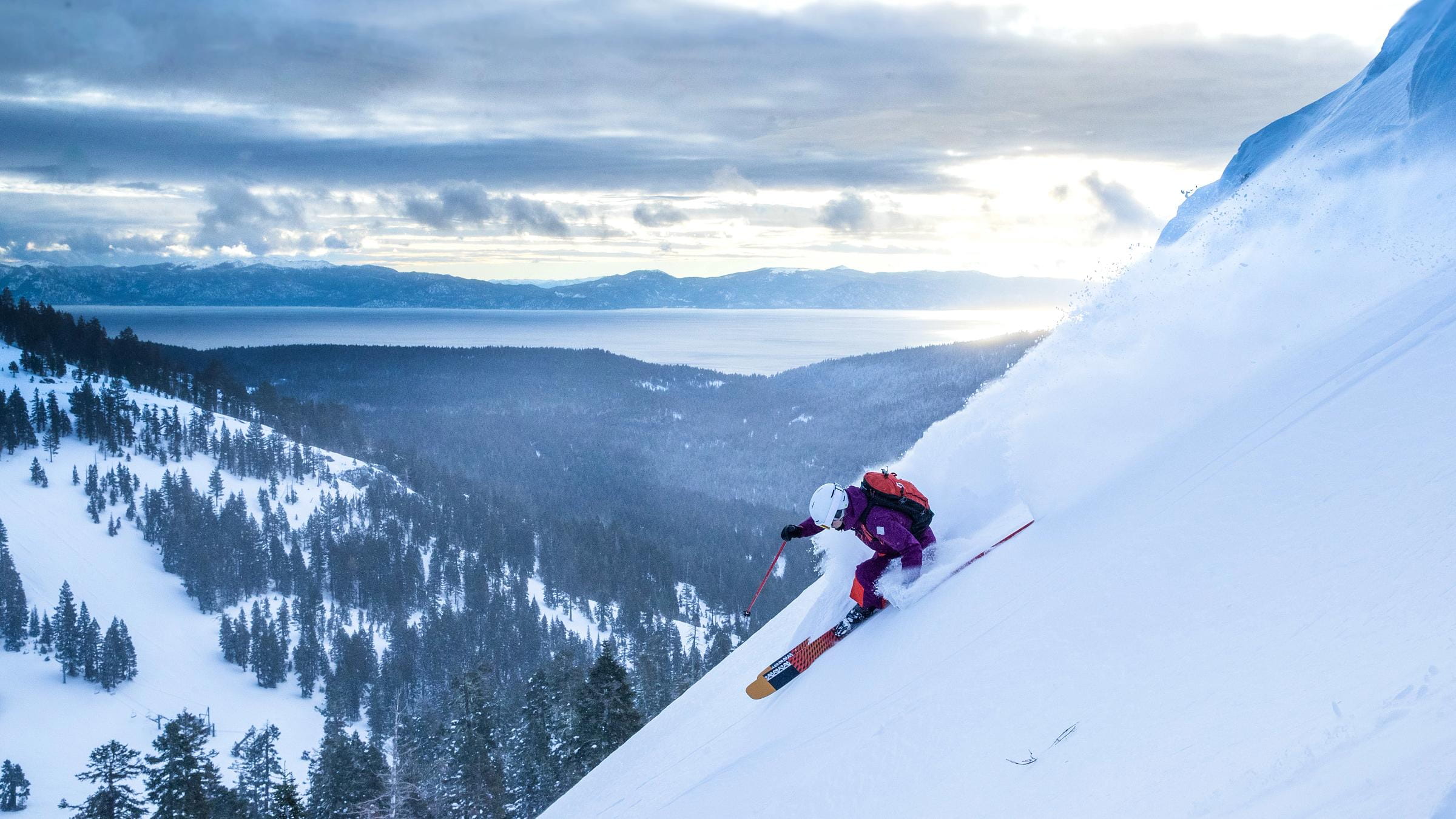 Skier off Treeline Cirque at Alpine Meadows on a powder day with Lake Tahoe in the background